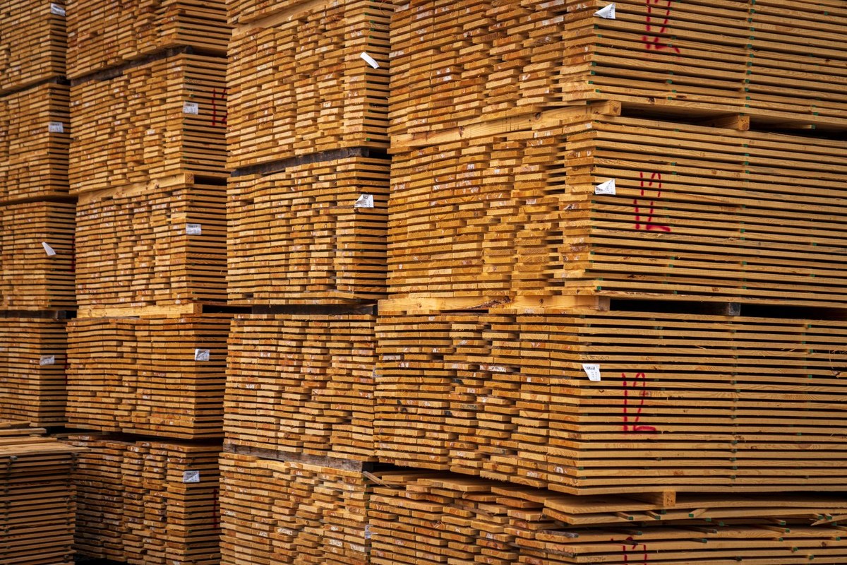 Stacked light timber planks in a warehouse with airflow stickers between layers